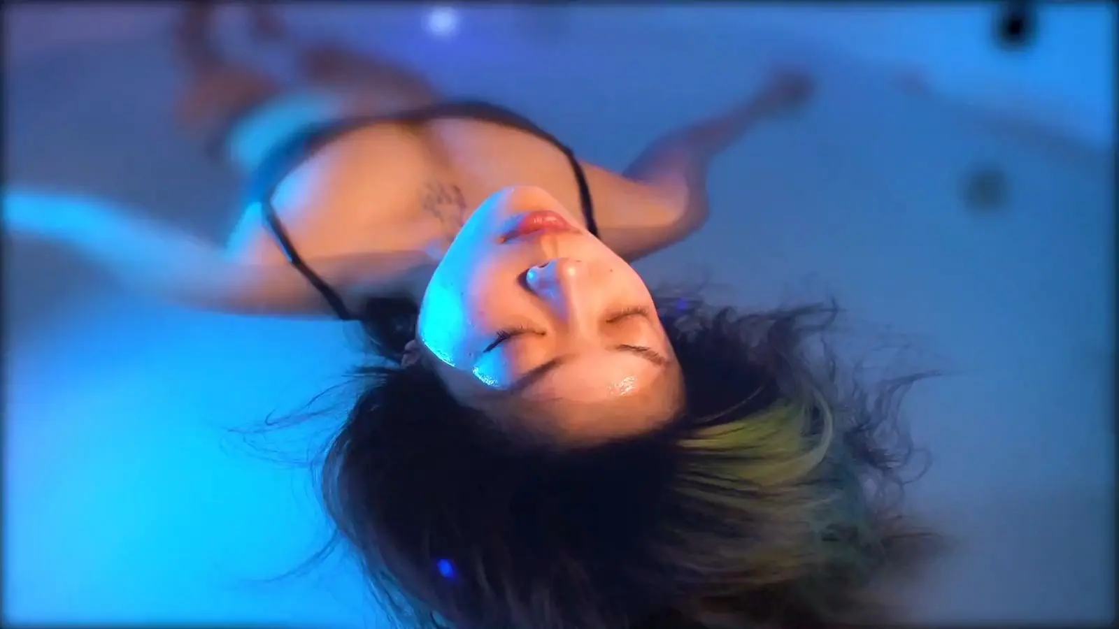 A guest floating in a blue-lit float suite