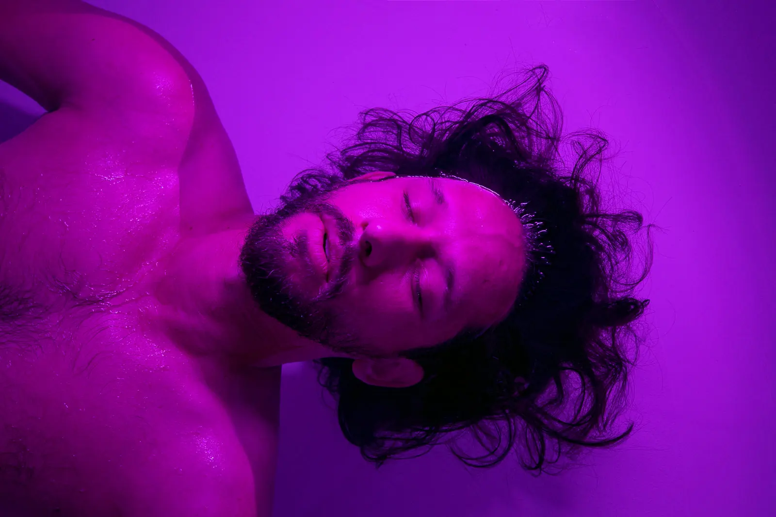 A guest resting in a violet-lit float suite