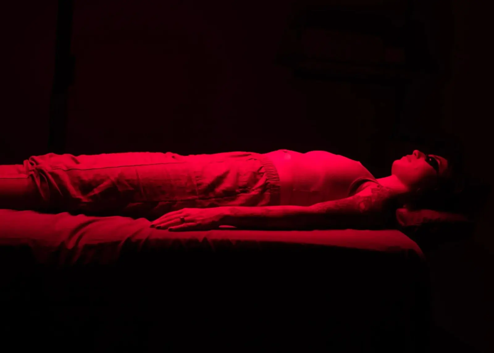 A guest resting on the vibroacoustic table under the red light panel